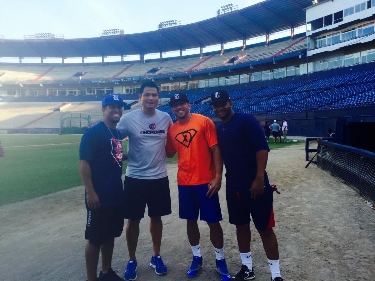 Four players standing on the warning track of a stadium